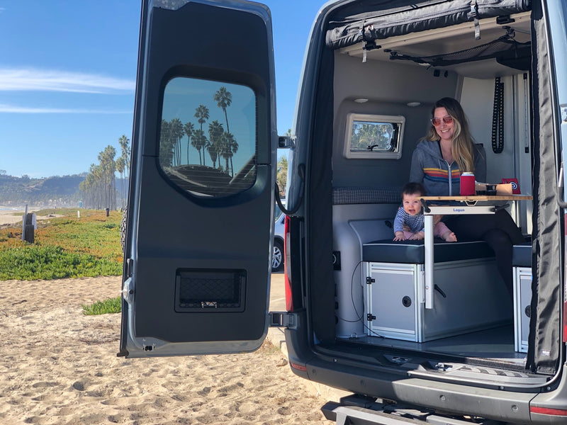 Beachfront RV rental: A woman and baby relax inside their camper van with open doors, overlooking the ocean. — photo 3