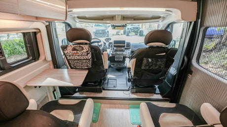 Inside this RV rental, the front cabin features swivel seats, a table, and scenic outdoor views.