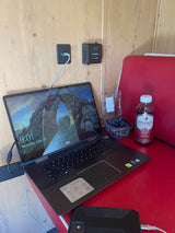 RV rental setup: Dell laptop, Dometic controls, kombucha, and blueberries on a red table, showing a mobile workspace.