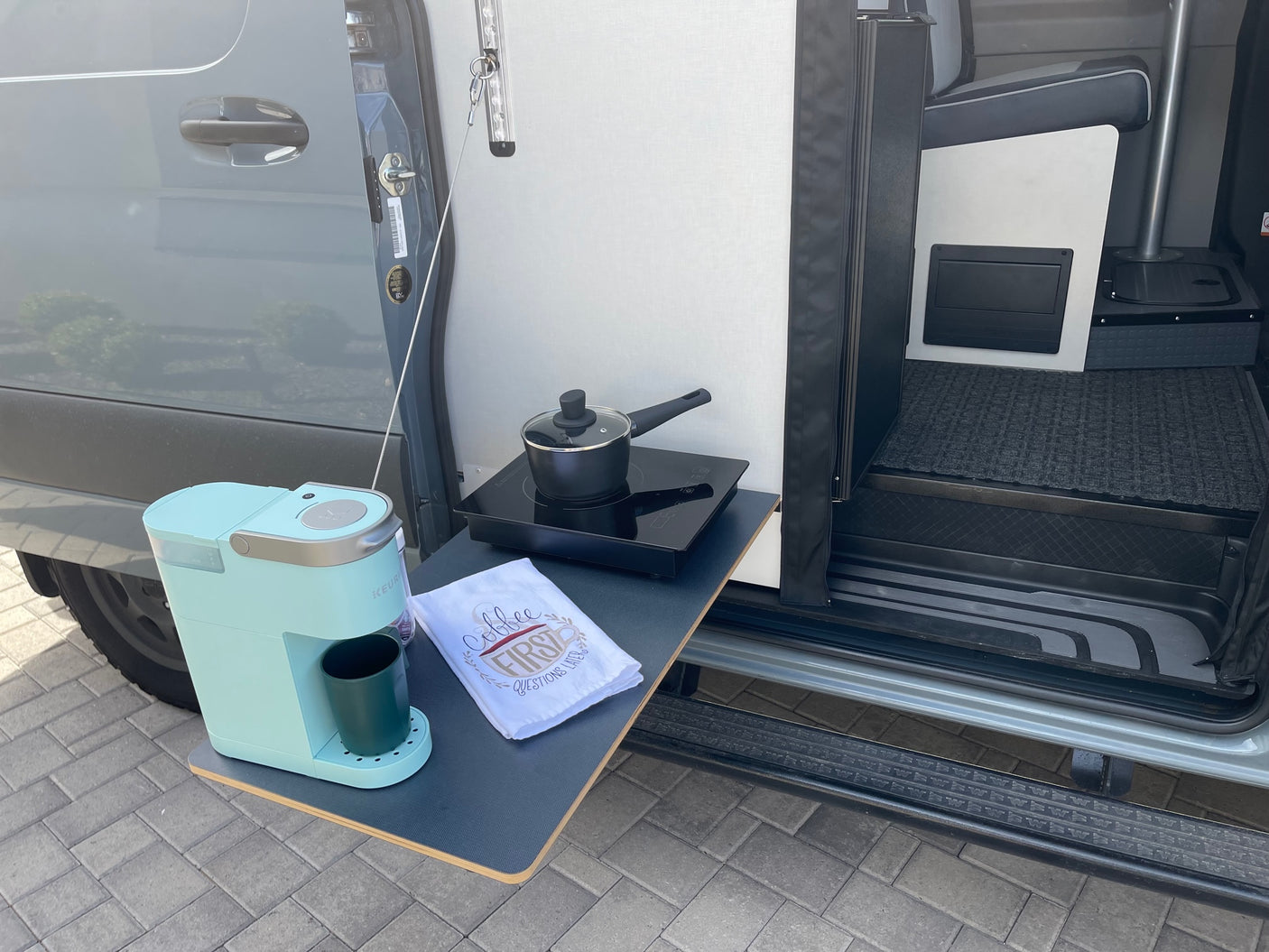 RV rental convenience: A pull-out counter with coffee maker & cooktop from a van's open side door.