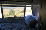 Cozy RV rental bedroom offering a stunning landscape view through the window. Experience comfort and nature on your travels.