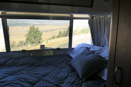 Cozy RV rental bedroom offering a stunning landscape view through the window. Experience comfort and nature on your travels.