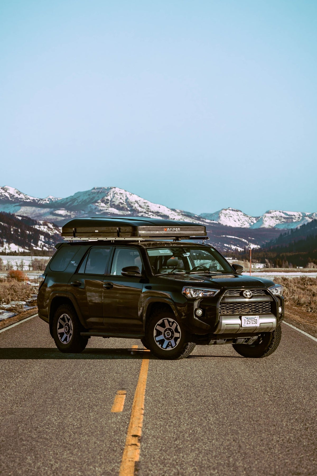 Black Toyota 4Runner with iKamper rooftop tent on a scenic road in snowy Montana mountains, perfect for an RV rental adventure. — photo 7