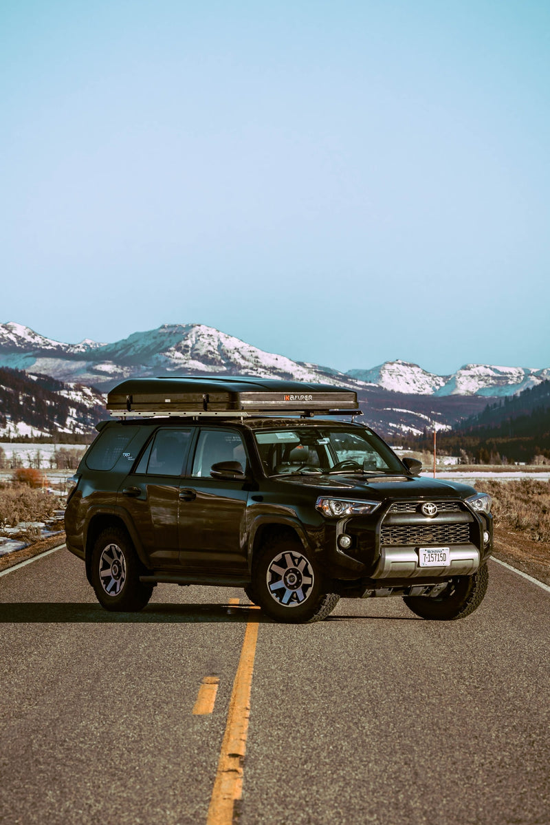 Black Toyota 4Runner with iKamper rooftop tent on a scenic road in snowy Montana mountains, perfect for an RV rental adventure. — photo 7