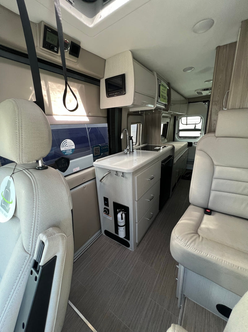  and a parked white van visible outside.|Dashboard of a Pleasure-Way RV — photo 6