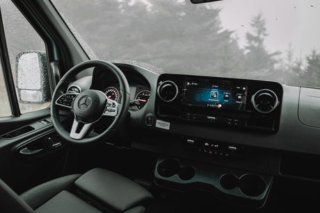 Inside a modern Mercedes-Benz van, ready for your next RV rental adventure on a rainy day. Shows the dashboard and infotainment.