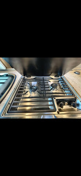 This RV rental features a stainless steel Dometic gas cooktop with two burners and controls, ready for your travel kitchen needs.