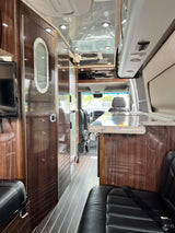 Experience comfort in this spacious RV rental interior with rich wood finishes, leather seats, and a functional galley.