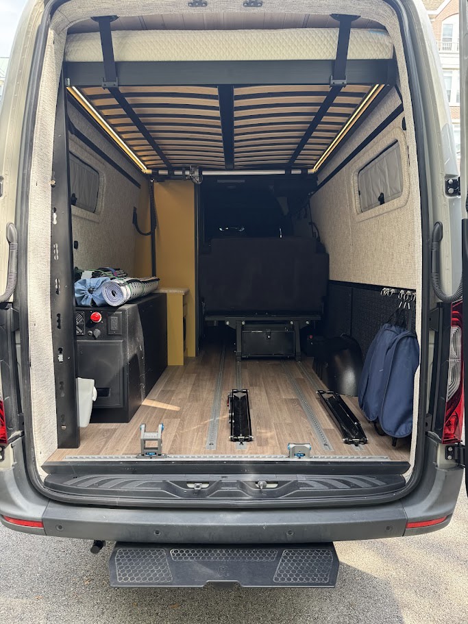 RV rental camper van's spacious rear with a raised bed, power station, and L-track flooring for flexible storage.