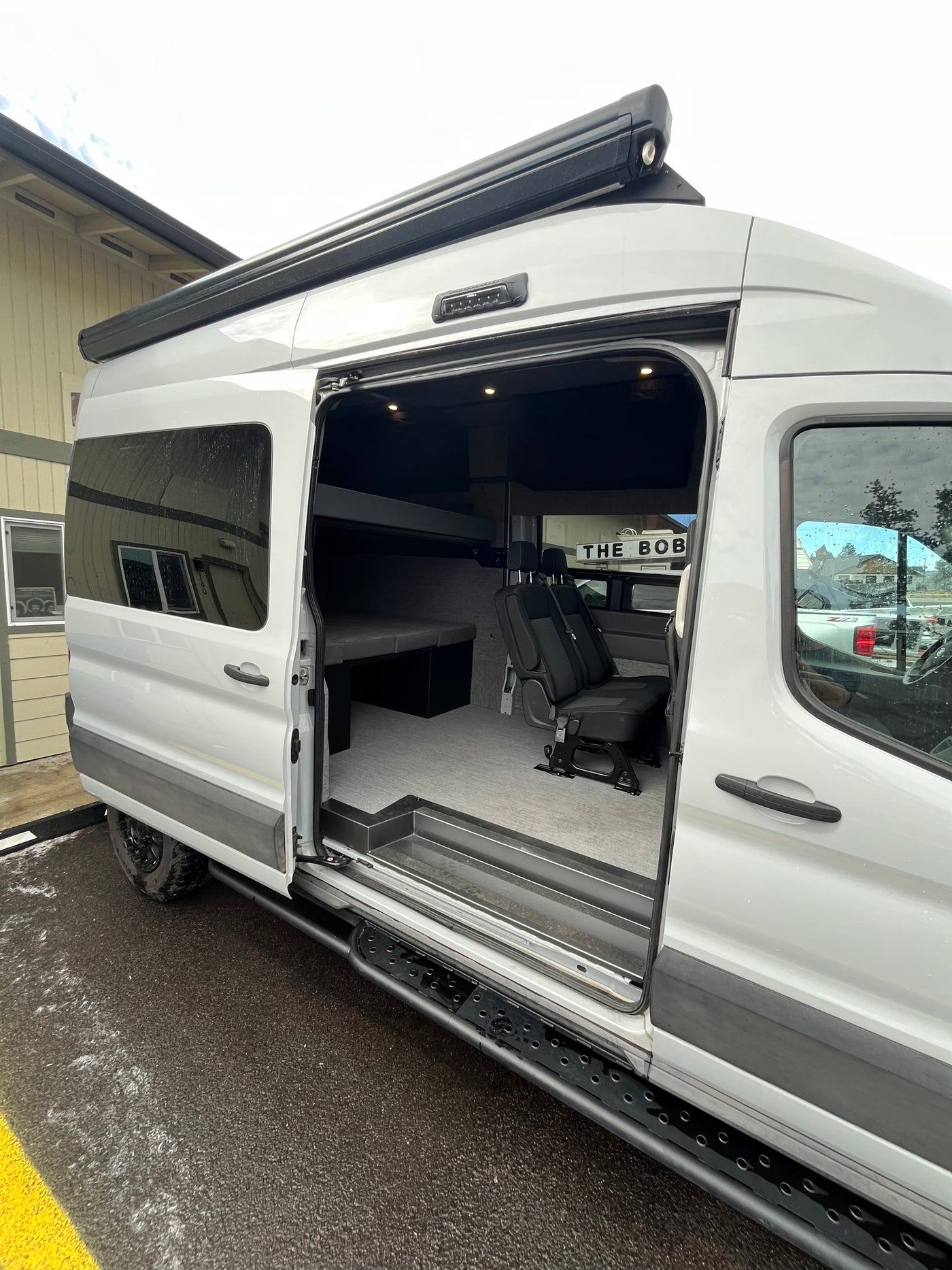 Modern white camper van rv rental, with its side door open, revealing a spacious, multi-functional interior setup. — photo 4