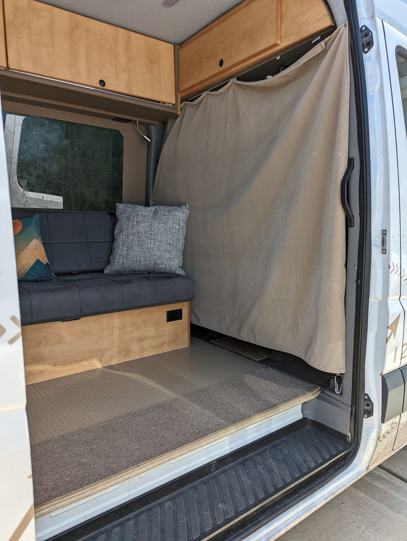 Camper van interior with a bench seat, wooden overhead cabinets, and a privacy curtain, ready for your rv rental adventure. — photo 10