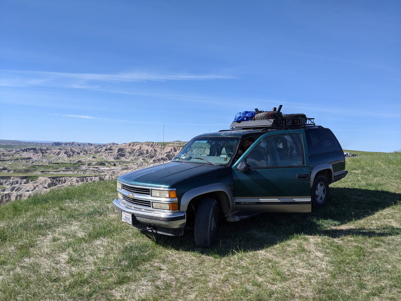 Adventure-ready green SUV, similar to an RV rental, overlooking the stunning Badlands landscape.