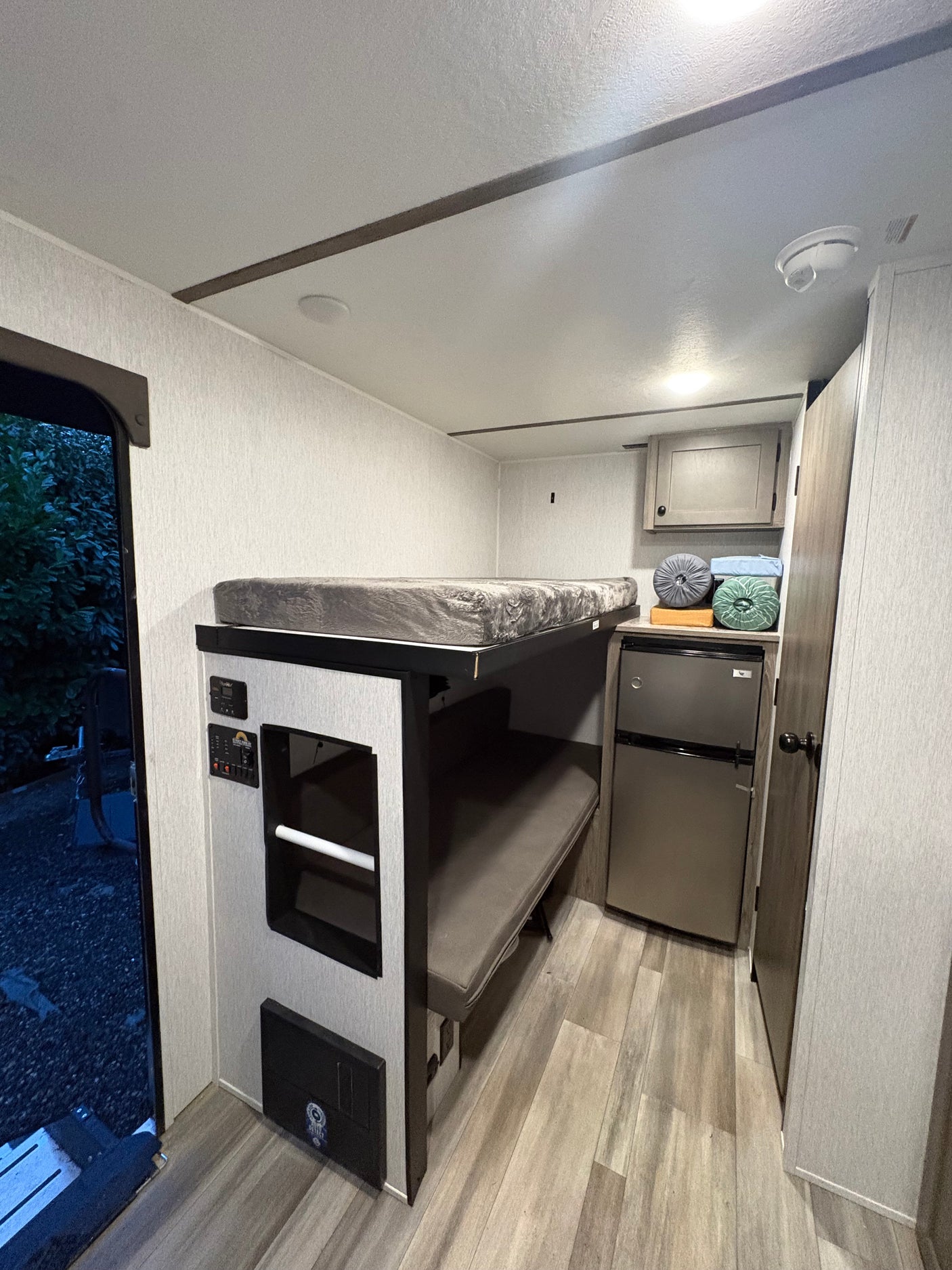 RV rental interior with bunk beds, a compact fridge, and control panels. A cozy, functional space for travel adventures.