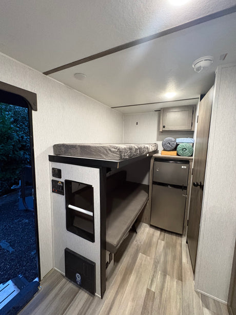 RV rental interior with bunk beds, a compact fridge, and control panels. A cozy, functional space for travel adventures.
