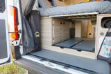 Explore this RV rental's clever camper van interior, featuring a raised bed, pull-out storage, and utilities at the rear.