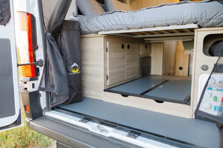 Explore this RV rental's clever camper van interior, featuring a raised bed, pull-out storage, and utilities at the rear.