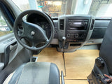 Interior of an RV rental: a converted van cabin with a wooden floor, steering wheel, and dashboard visible.