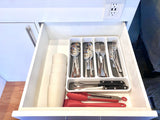 Inside an RV rental's organized kitchen drawer: neatly arranged cutlery, cooking tools, and stackable cups. An efficient setup.