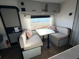 RV rental interior: A bright, modern dinette with comfy benches, table, and overhead storage, perfect for meals and relaxation on the road.