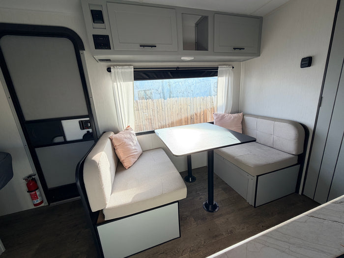 RV rental interior: A bright, modern dinette with comfy benches, table, and overhead storage, perfect for meals and relaxation on the road.