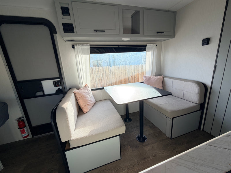 RV rental interior: A bright, modern dinette with comfy benches, table, and overhead storage, perfect for meals and relaxation on the road. — photo 4