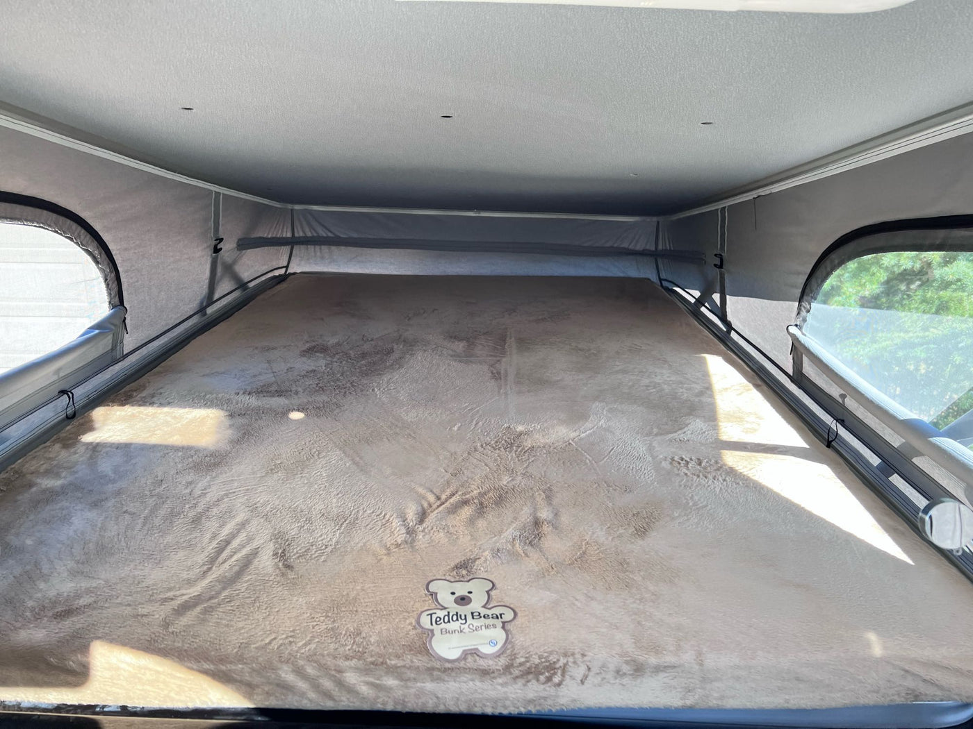 View of the comfortable pop-top sleeping area in an RV rental, complete with a fuzzy brown 'Teddy Bear Bunk Series' mattress. — photo 14