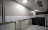 Modern RV rental sleeping area featuring bright overhead cabinets, LED lighting, and AC, ensuring a comfortable travel experience.