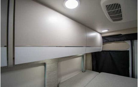 Modern RV rental sleeping area featuring bright overhead cabinets, LED lighting, and AC, ensuring a comfortable travel experience.