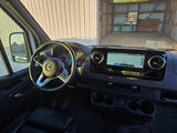 Inside a Mercedes-Benz RV rental: a modern cockpit with steering wheel, navigation screen, and cupholders.