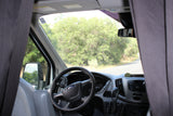 RV rental van interior: Steering wheel and dashboard visible, with a road and trees through the cracked windshield.
