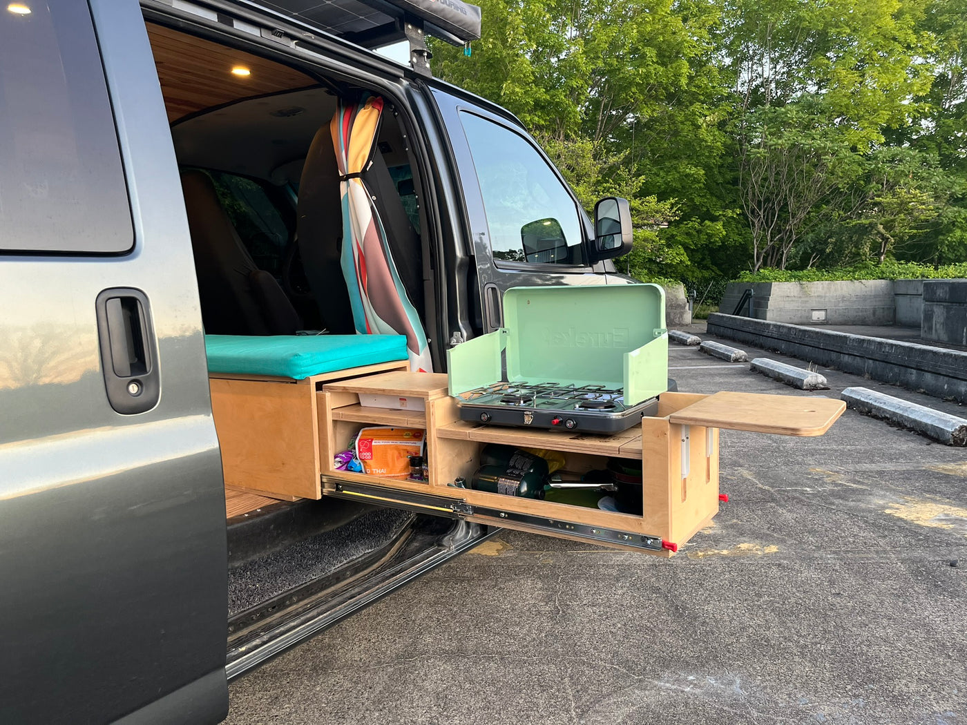 Open side door of an RV rental reveals a custom interior & a pull-out outdoor kitchen with a gas stove. — photo 5