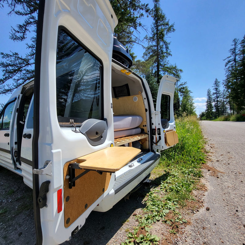  and back windows.|RV rental camper bed frame and storage area: A wooden slatted bed platform with a central support leg over a black rubber floor.|Explore this RV rental's converted van interior — photo 15