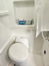 Explore your RV rental's compact wet bath, featuring a toilet, shower area with curtain, and convenient wall-mounted toiletries.