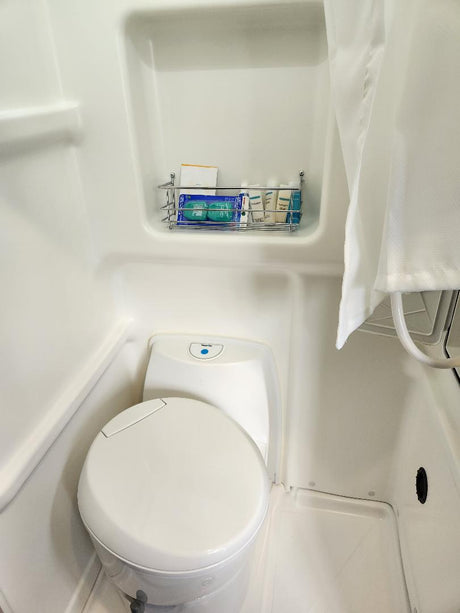 Explore your RV rental's compact wet bath, featuring a toilet, shower area with curtain, and convenient wall-mounted toiletries.