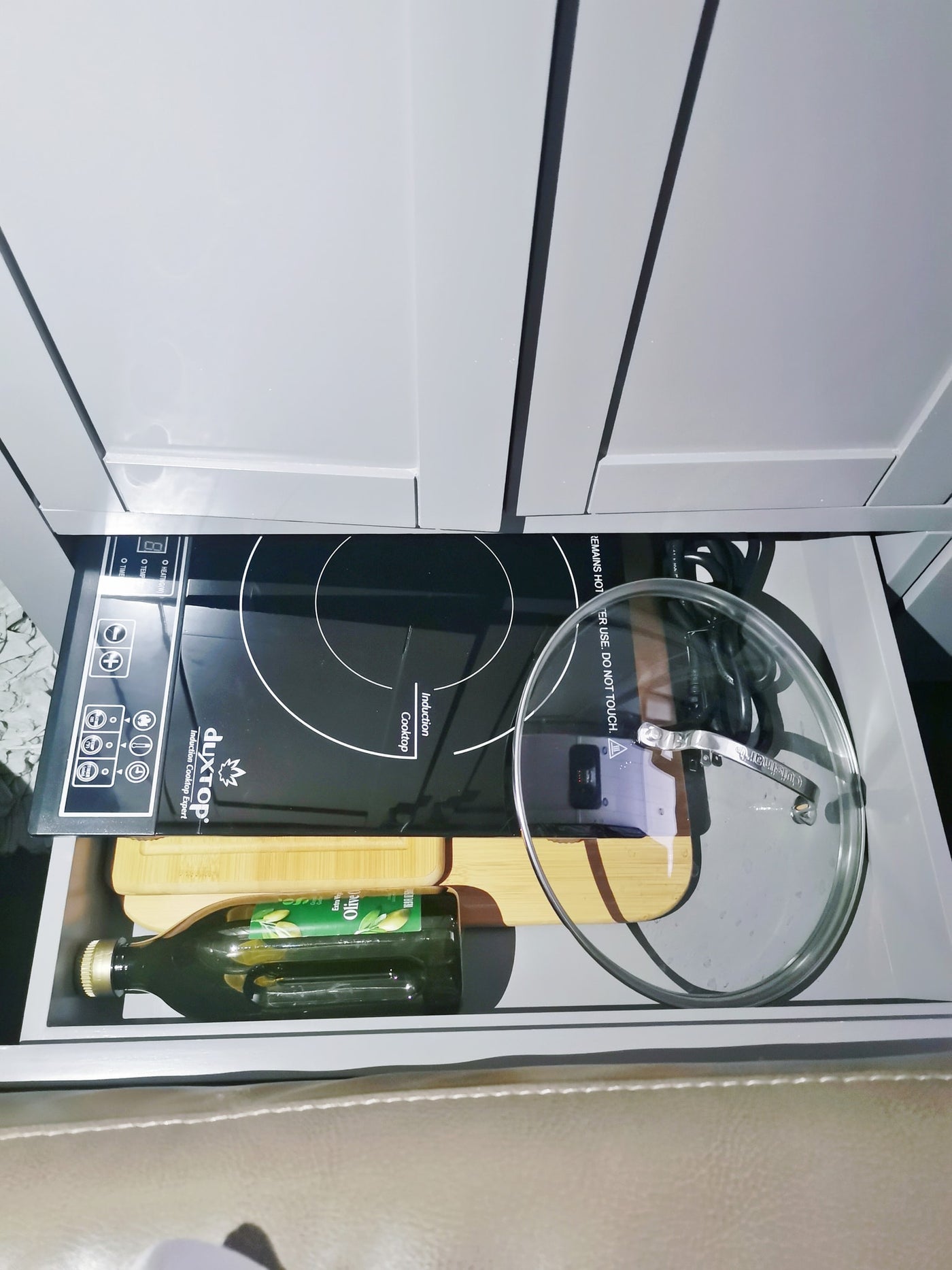 Compact RV rental kitchen drawer: a Duxtop induction cooktop, olive oil bottle, and Cuisinart lid for cooking on the go. — photo 11