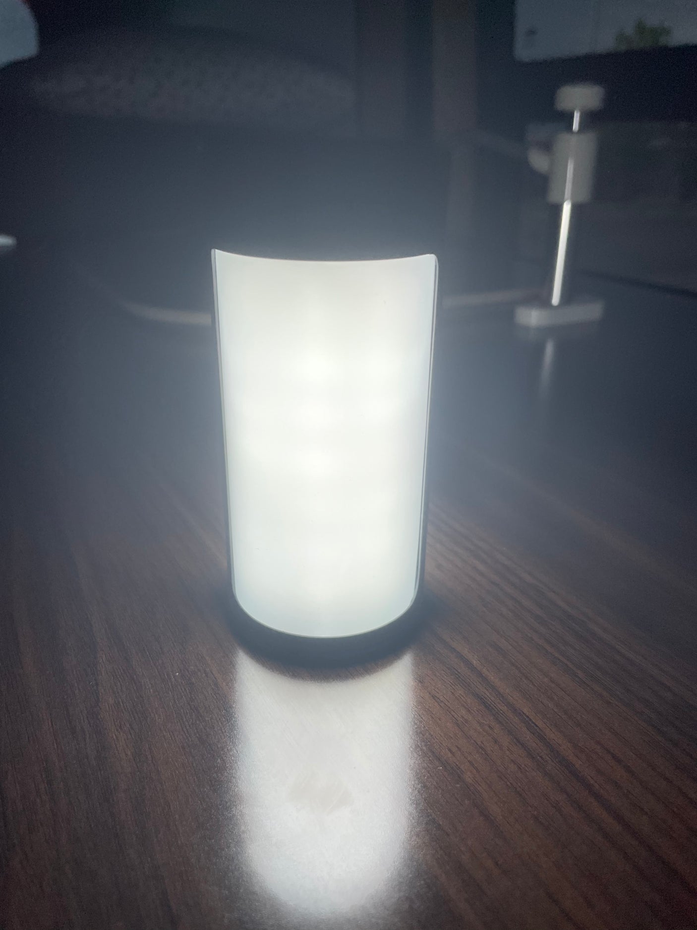 A white, glowing portable light on a dark wood table, perfect for your RV rental adventures.