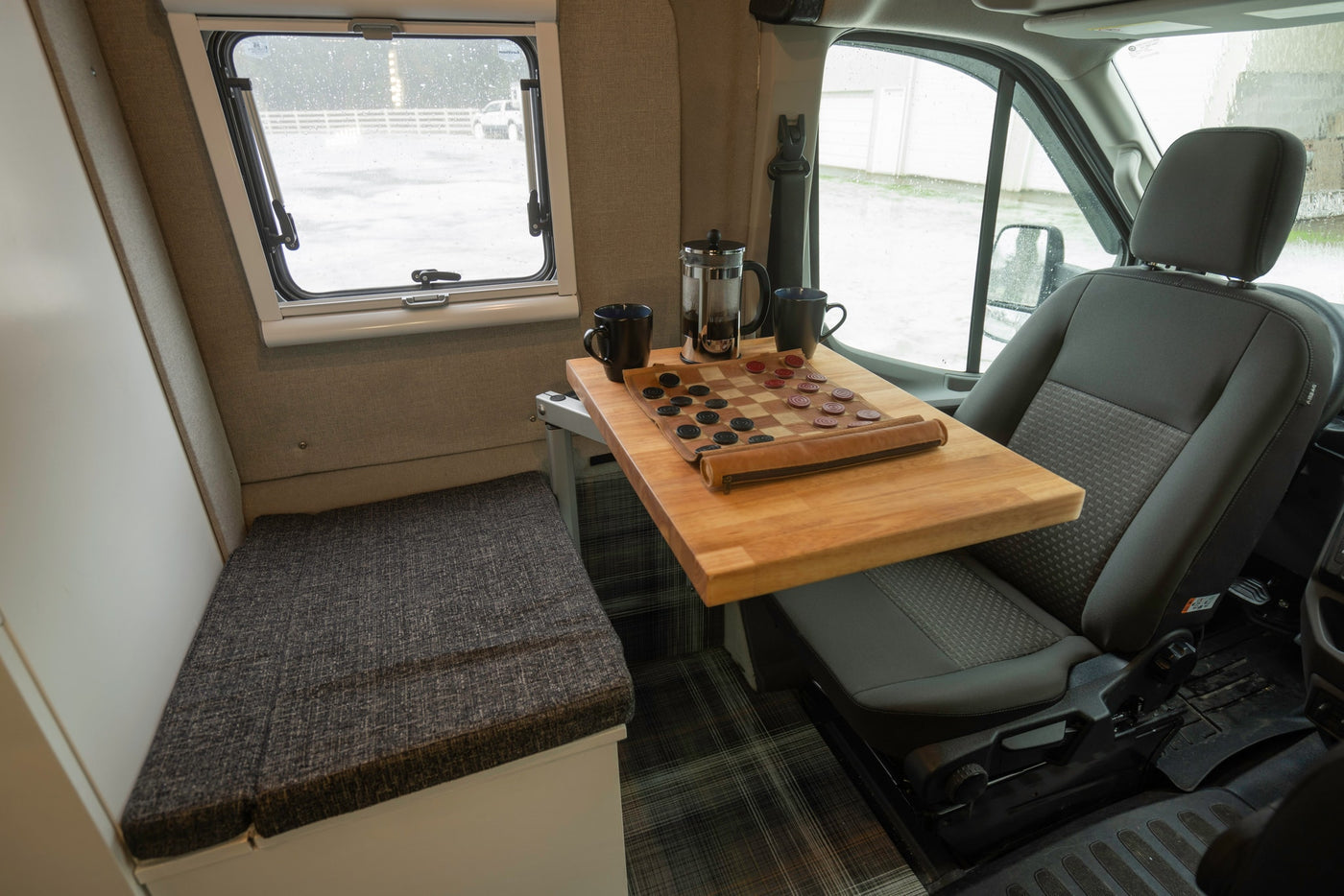Cozy RV rental interior featuring a wooden table with a checkers game, coffee, and a comfortable bench seat. — photo 9