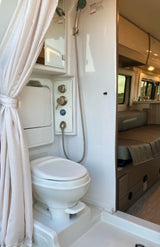 RV rental interior featuring a compact bathroom with shower, toilet, and adjacent living space.