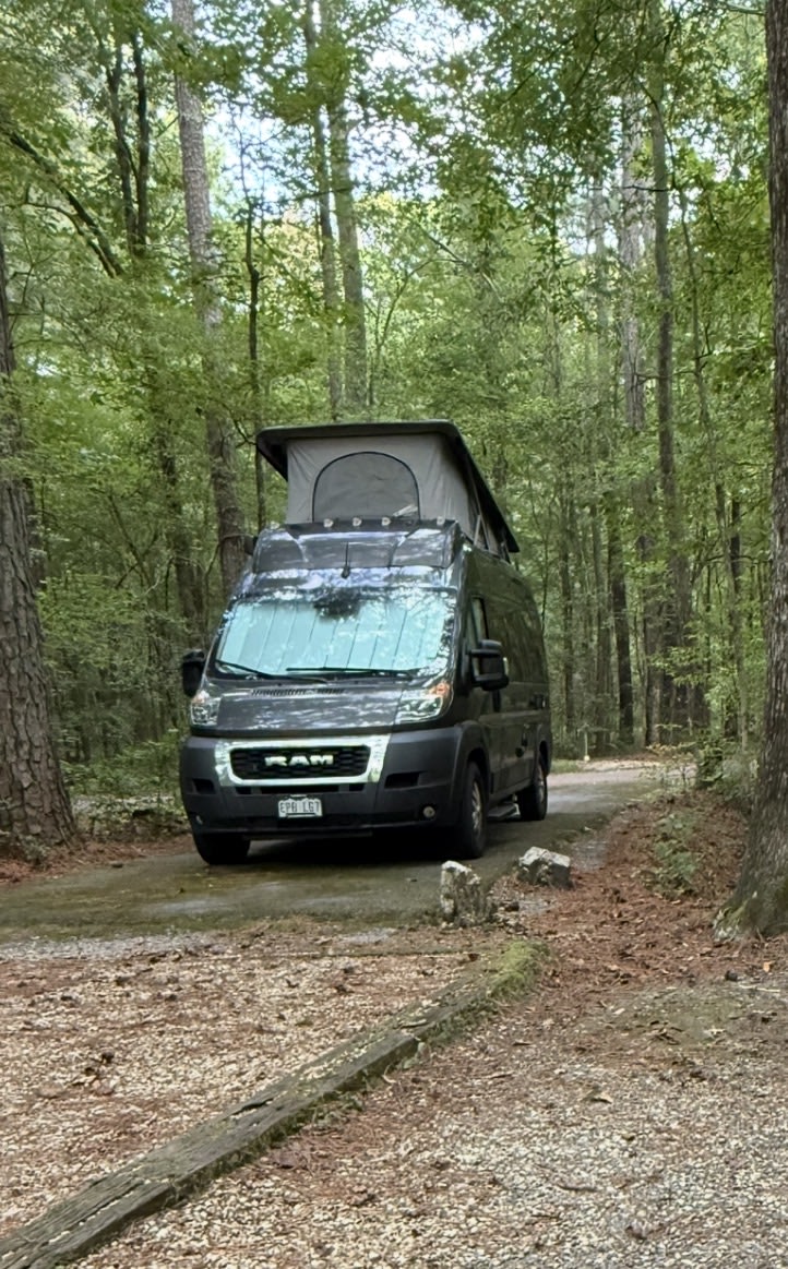 RV rental camper van parked in a lush forest campsite