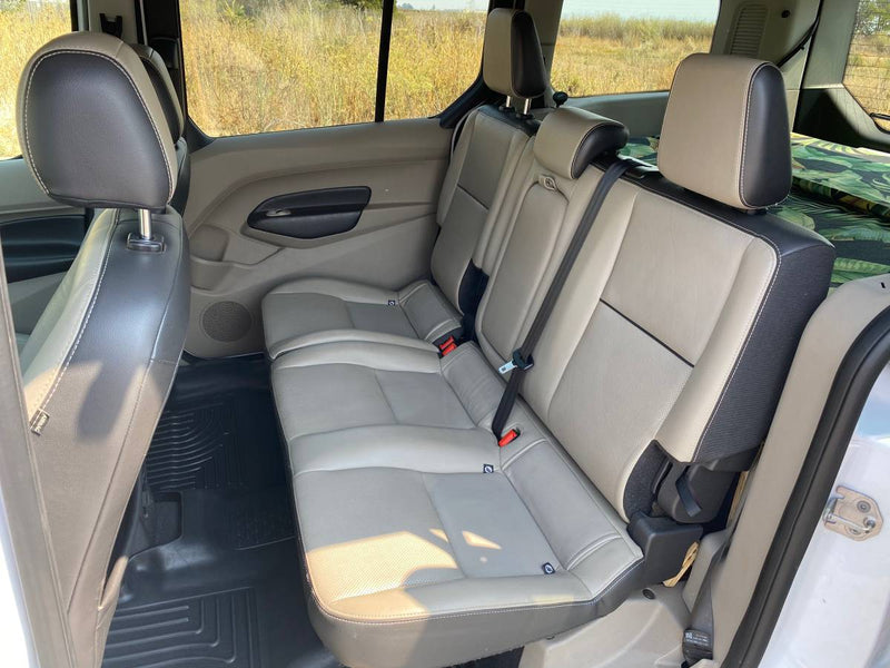  clear sky.|White van (like an RV rental) with cargo box parked on a forest road among sunlit towering redwood trees.|Experience lakeside serenity! This Ford Transit Connect RV rental is parked among pines — photo 3