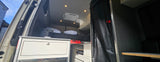Inside this RV rental: a comfy bed, overhead AC unit, and kitchen storage, perfect for your next road trip.