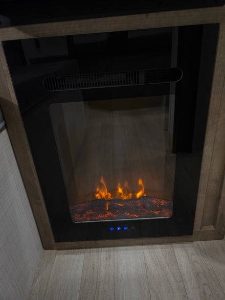 An electric fireplace with glowing faux flames and logs in an RV rental, showing control buttons below. Adds warmth & ambiance.