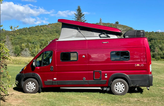 This vibrant red Winnebago Solis camper van is perfect for an RV rental adventure, parked outdoors with its pop-top raised.