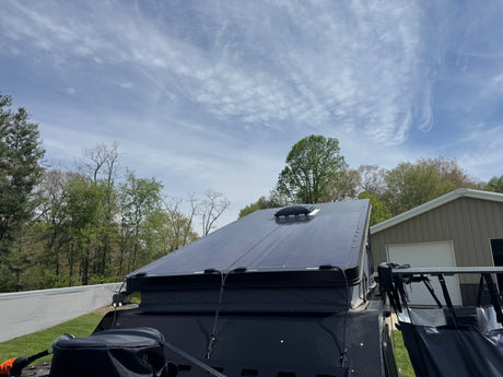 Top view of an RV rental with sleek solar panels on the roof, ready for off-grid excursions under a partly cloudy sky.