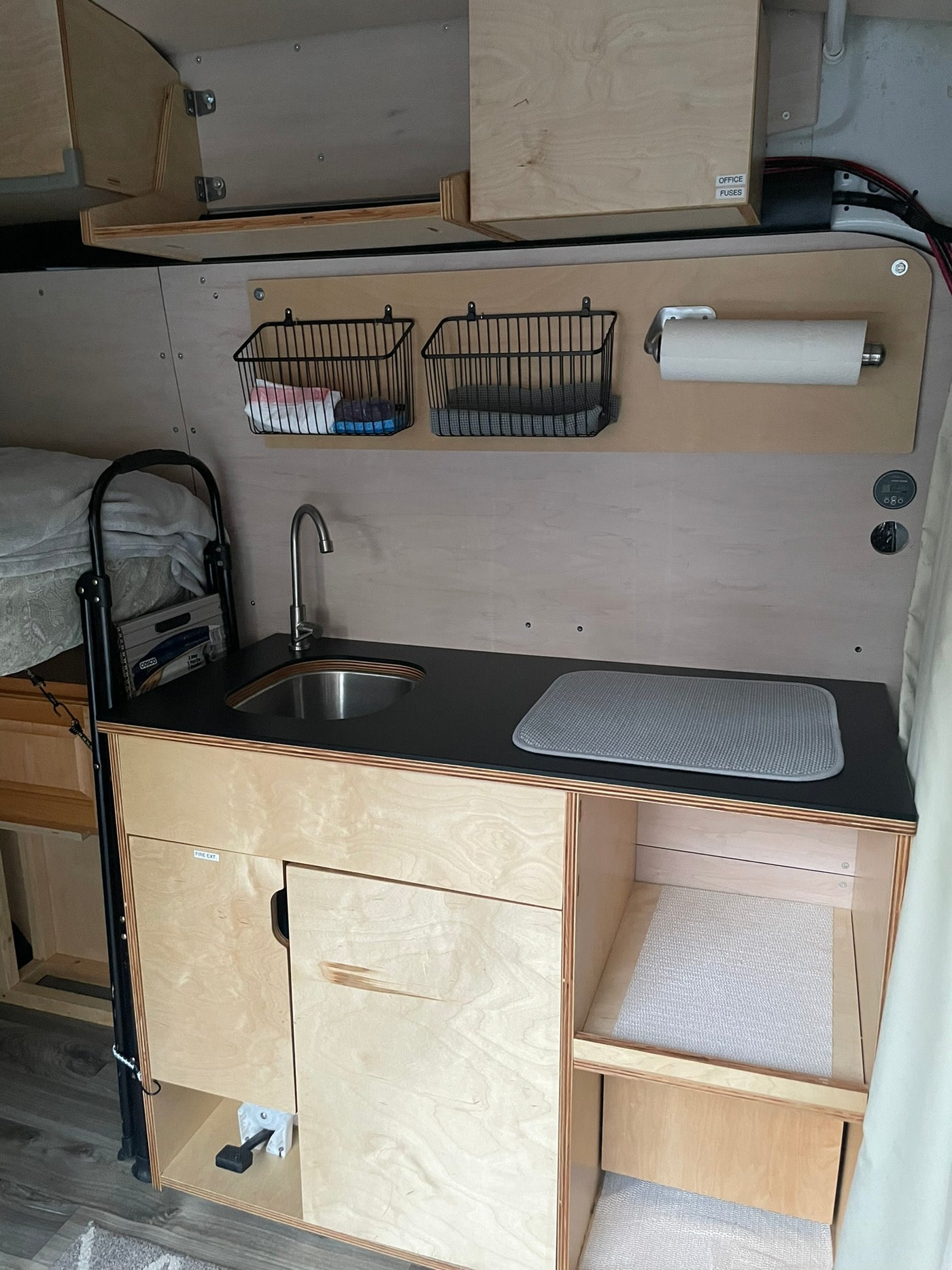 View of a functional RV rental kitchenette: sink, smart storage, paper towels, and wood cabinetry. — photo 7