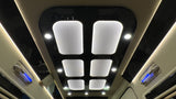 Luxury RV rental ceiling showcases modern design: bright white panel lights, accent lights, and blue ambient grab handles.