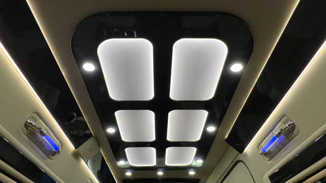 Luxury RV rental ceiling showcases modern design: bright white panel lights, accent lights, and blue ambient grab handles.