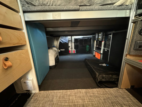 RV rental's under-bed storage organized: wood drawers, power outlet, generator, Thule bag, & sleeping pad.
