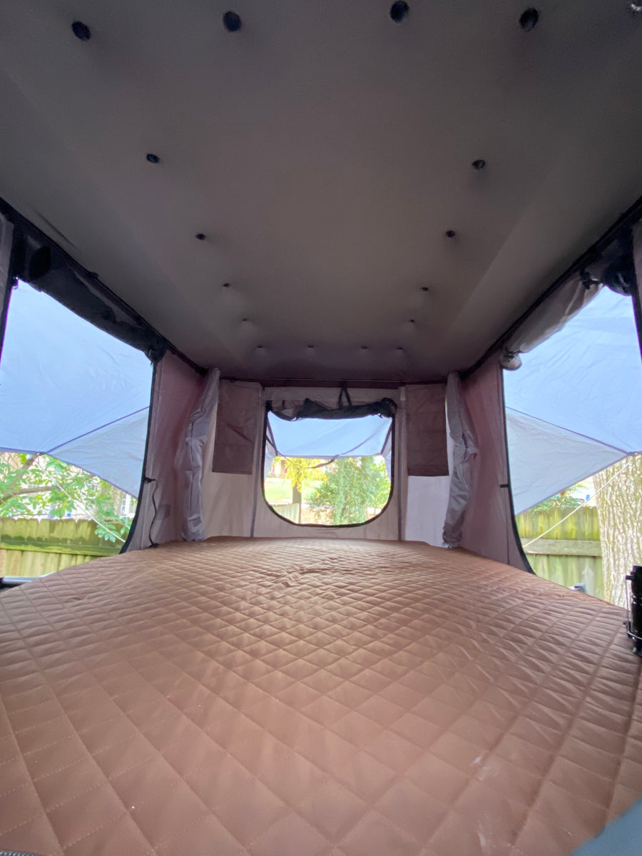 Spacious rooftop tent interior with a plush, quilted sleeping pad – ideal for your next RV rental getaway.