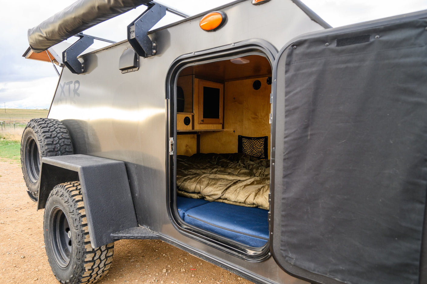 Explore this rugged off-road teardrop trailer, great for an rv rental and adventure camping, featuring a cozy bed.
